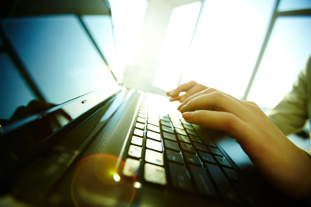 Hands typing on a laptop keyboard